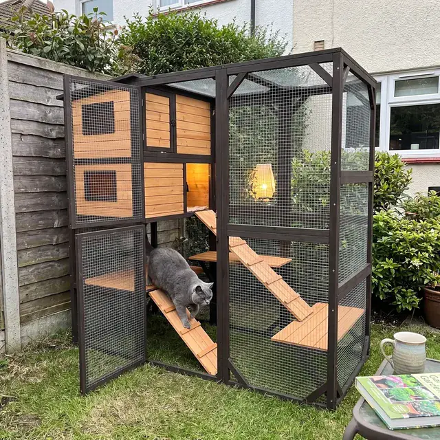 Dunkelbraunes zweistöckiges Katzenhaus aus Holz mit Rampen und Gitter im Garten